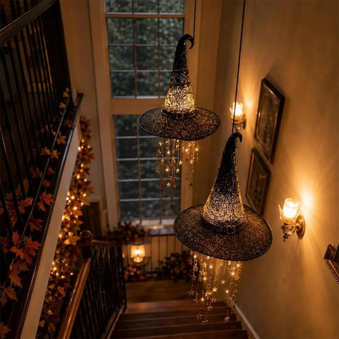 Hanging witch hats with warm lights decorating an indoor staircase